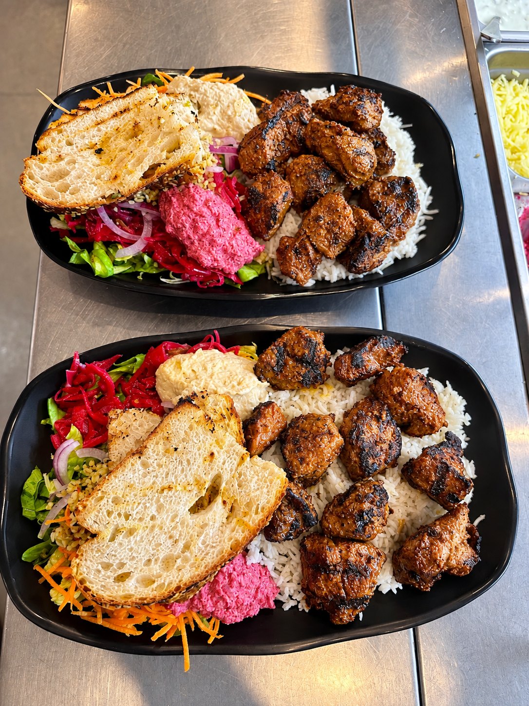 Two chargrill plates with rice, salad, dips and Turkish bread